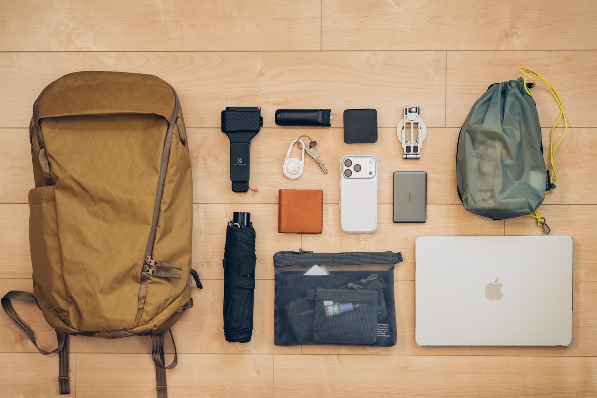 Able Carry Daybreaker 2と、MacBookや折りたたみ傘、ポーチなど収納する荷物を床に並べた様子